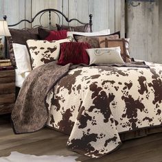 a bed covered in brown and white cow print comforter next to a night stand