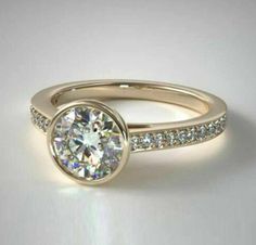 a yellow gold ring with diamonds on the side and a round diamond in the center