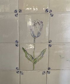 a white tile wall with a flower painted on it