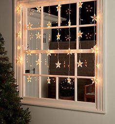 the window is decorated with christmas lights and garlands, as well as a small tree