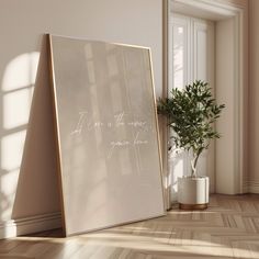 an empty room with a plant in the corner and a framed photograph on the floor