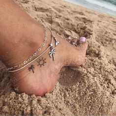 a woman's foot with tattoos on the beach