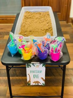 a table topped with lots of sand and plastic containers filled with different types of toys