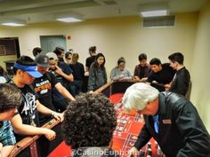 a group of people playing roulend in a room with red carpet and walls