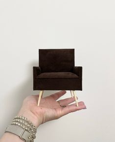 a person holding up a miniature chair in their hand