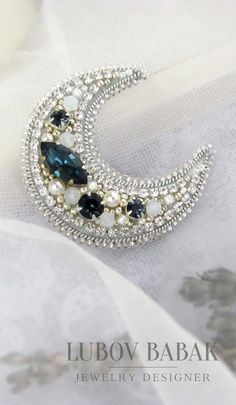 a brooch that is sitting on top of a white cloth with pearls and crystals