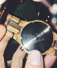 a person holding a wooden watch with the words our love is class written on it