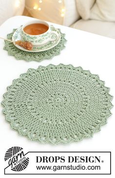 a cup of coffee sitting on top of a white table next to a doily