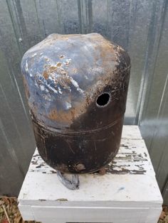 an old metal tank sitting on top of a white box