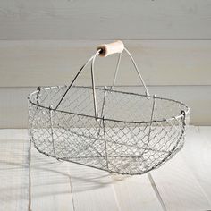 a wire basket with a wooden handle on a white wood floor, holding a piece of bread