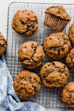 chocolate chip muffins on a cooling rack with a blue towel next to them