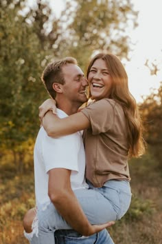 a man holding a woman in his arms and smiling at the camera while she holds him close to her chest