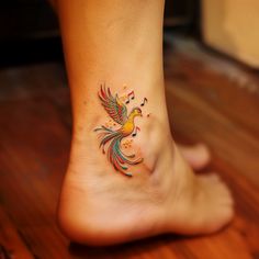 a colorful bird tattoo on the foot of a woman's left leg, with music notes all over it