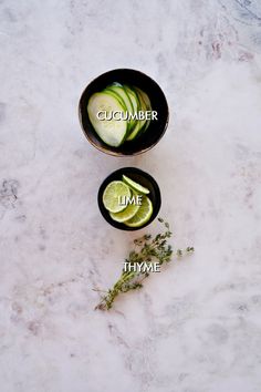 cucumber, lime and thyme in bowls on a marble surface