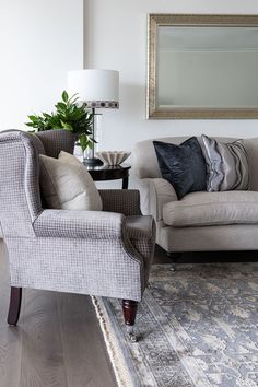 a living room with two couches and a rug in front of a large mirror