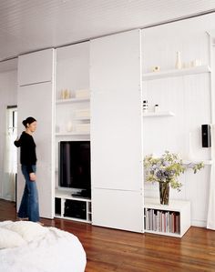 a woman is standing in the living room looking at something on the wall behind her