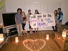 a group of people holding a sign in the shape of a heart with candles around it