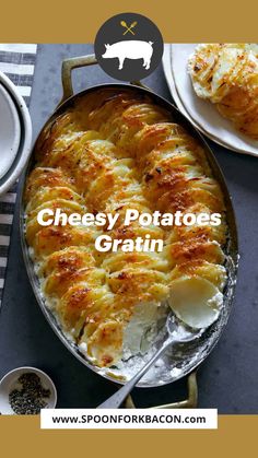 an oval casserole dish with potatoes and cheese on the side next to two plates