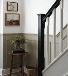 a wooden table sitting under a stair case next to a bannister with plants on it