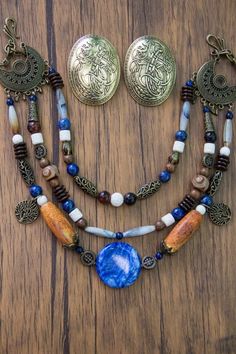 a necklace and earring set on a wooden table with two medallions hanging from it