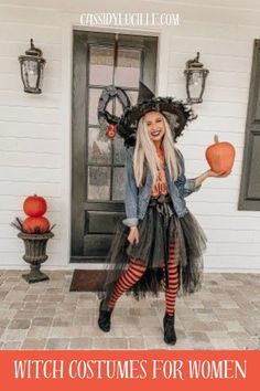 a woman dressed as a witch holding an orange pumpkin in front of a white house