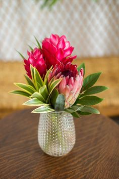 a vase filled with pink flowers on top of a wooden table