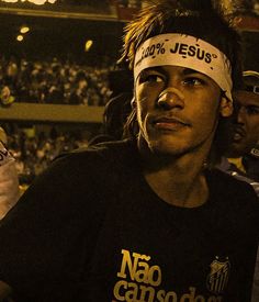 a man with a headband on standing in front of an audience at a sporting event