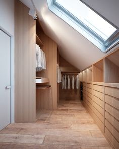 an attic bedroom with wooden closets and skylight above the walk - in closet