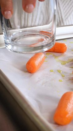 the carrots are being peeled and placed in front of a glass with water on it