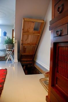 an open door leading to a room with a red rug on the floor and a wooden cabinet