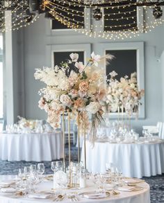 an elegant centerpiece is adorned with flowers and greenery for a wedding reception in the ballroom