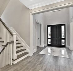 an empty entryway with stairs and black door