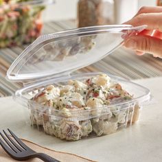 a plastic container filled with food sitting on top of a table next to a fork