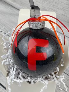 a black and red ornament with the letter f on it in a box