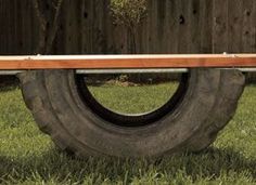 a bench made out of old tires sitting in the grass