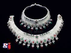 an elaborate necklace and earring set with red, green and white stones