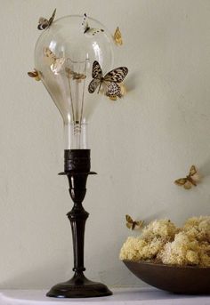 a light bulb sitting on top of a table next to a bowl filled with flowers