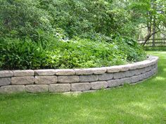 a stone wall in the middle of a grassy area