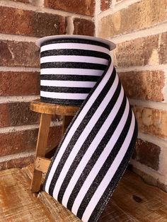 two black and white striped hats sitting on top of a wooden chair next to a brick wall