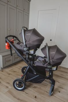 two baby strollers sitting on top of a hard wood floor in a room with gray cabinets