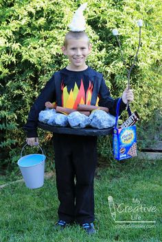 a young boy holding a tray with marshmallows and hot dogs on it