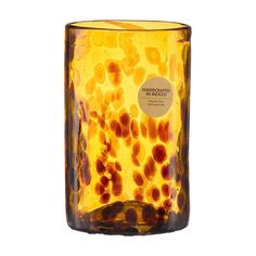 a glass vase with yellow and brown designs on it's sides, set against a white background