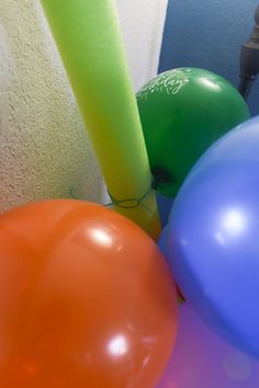 several balloons are tied to the wall with one green and one orange balloon in it