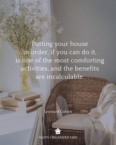 a wicker chair sitting in front of a window next to a vase with flowers