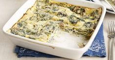 a casserole with spinach and cheese in a white dish on a table