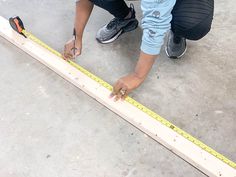 a woman measuring the length of a piece of wood