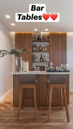 two bar stools sit in front of an open shelf with bottles and glasses on it