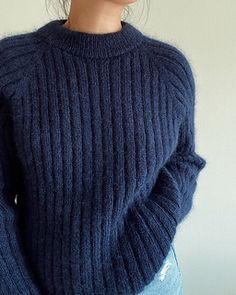 a close up of a doll wearing a blue sweater and jeans with her hands in her pockets