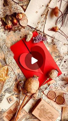 a red envelope with a heart on it surrounded by other decorative items and dried flowers