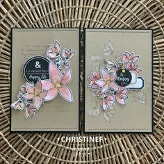 two cards with flowers on them sitting next to each other in front of a wicker basket